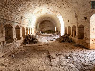 Un alto portale ci conduce al suo interno: un lungo stanzone con decine di aperture destinate a mucche e cavalli